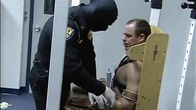 Leather-clad cop takes down a restrained inmate in a rough bondage scene