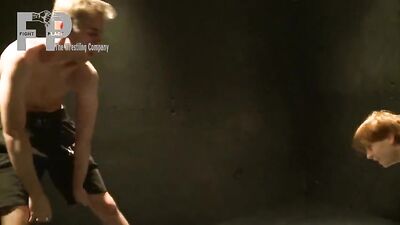 Muscular men grappling in a muddy ring