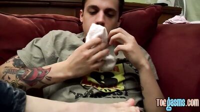 Tattooed twink gets a footjob before getting to blow cock